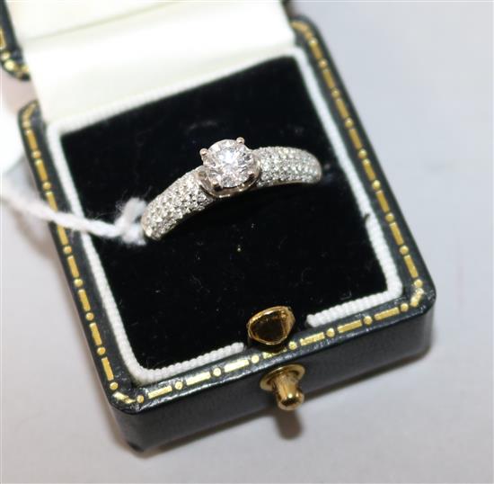 A modern claw set single stone diamond ring with diamond encrusted shoulders, size O.